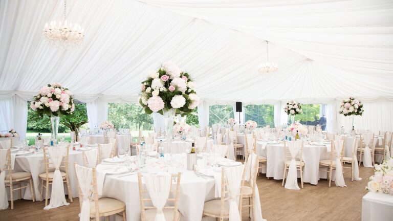 The marquee laid for a wedding breakfast with round tables, chandeliers and pink and white flowers, That Amazing Place