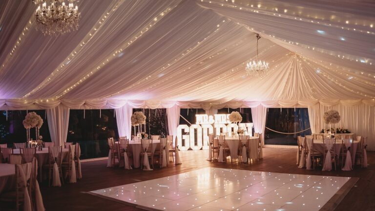 The marquee at night with fairy lights in the ceiling linings, chandeliers and an illuminated dance floor, That Amazing Place