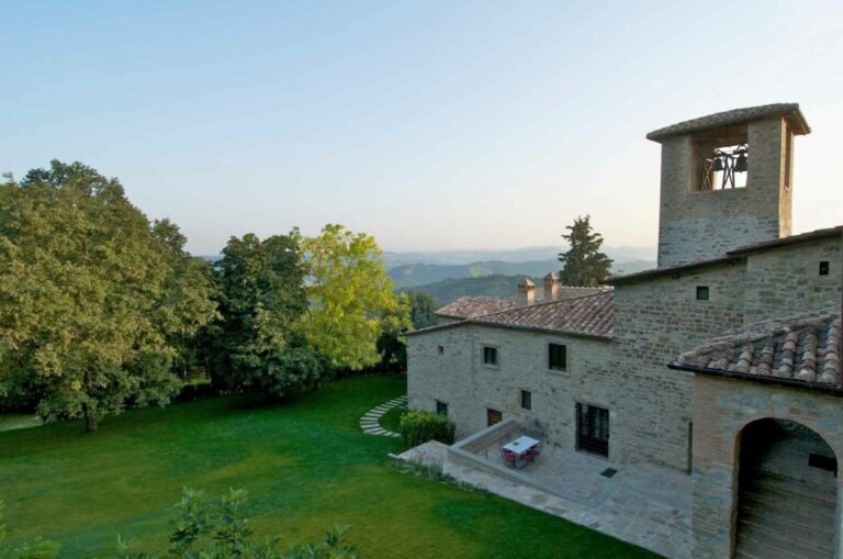 The medieval abbey in its gardens, the wooded hills of Umbria beyond, The Abbazia San Faustino