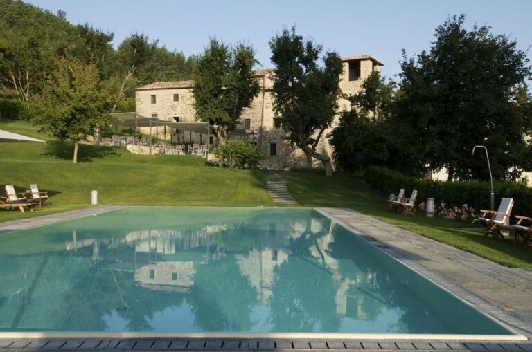 The heated pool on the lawn, the abbey and its cypress trees behind, The Abbazia San Faustino