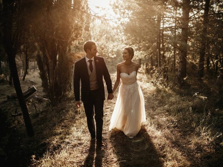 A couple hand in hand in the golden woods of the estate, The Abbazia San Faustino