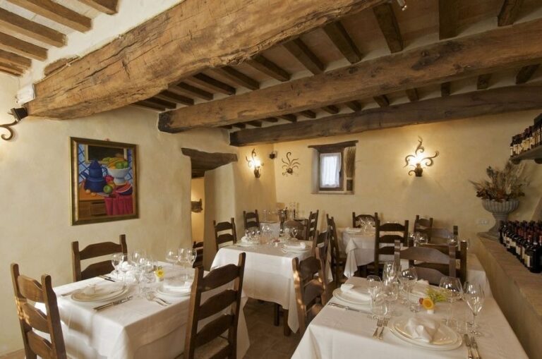 A vaulted dining room laid with white linen and candlelight, The Abbazia San Faustino