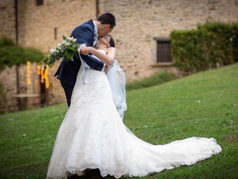 The groom and bride in the abbey garden, her train sweeping the grass, The Abbazia San Faustino