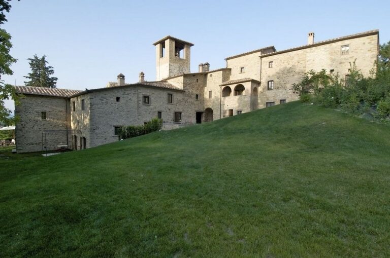 The abbey on its green hillside, stone walls and the bell tower, The Abbazia San Faustino