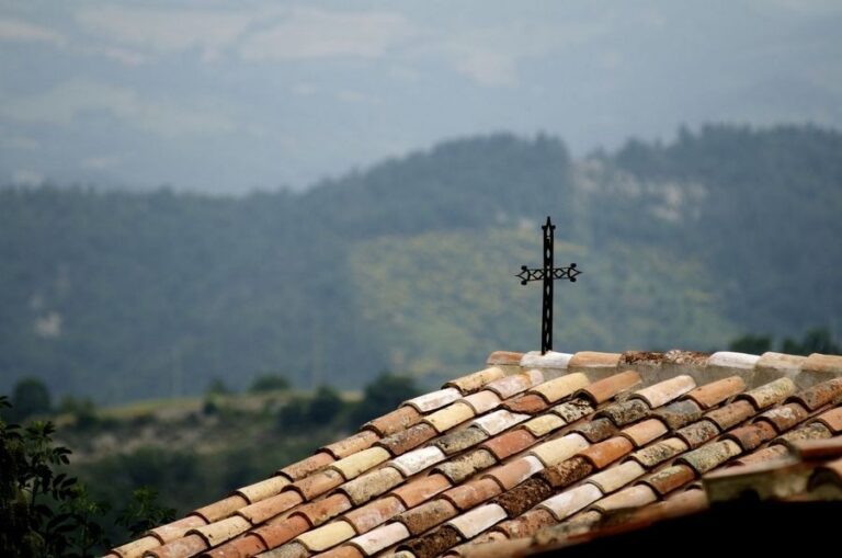 The iron cross on the tiled roof, the Umbrian valley beyond, The Abbazia San Faustino