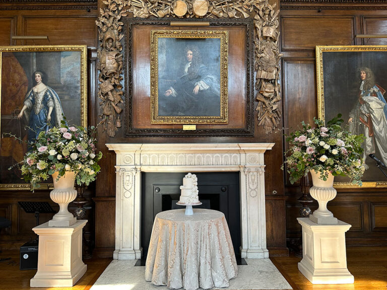 Wedding cake on a table between urns of flowers in a panelled room, The Admirable Crichton