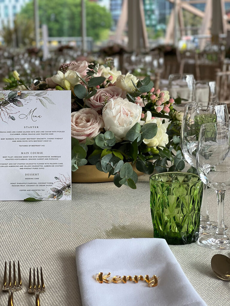 Table setting with a printed menu, green glassware and a name place card, The Admirable Crichton