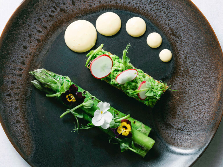 Asparagus roulade with radish and pansies on a dark plate, The Admirable Crichton