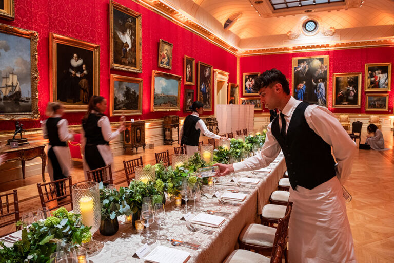 Waiter laying a long table in a red-walled gallery, The Admirable Crichton