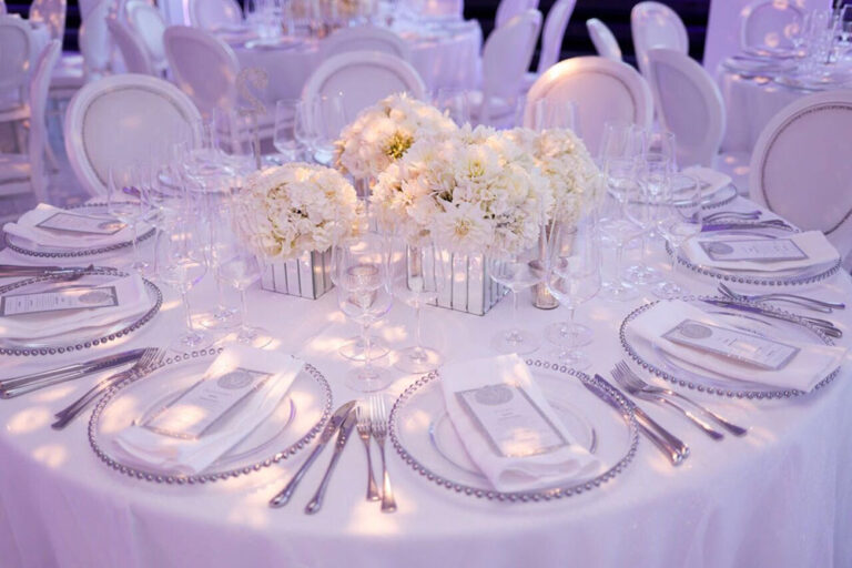 Round tables with white floral centrepieces and charger plates, The Admirable Crichton