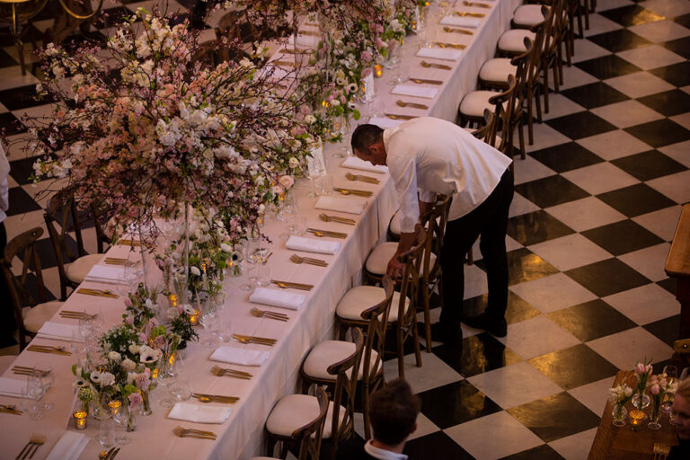 Long banquet table with blossom garland on a black and white marble floor, The Admirable Crichton