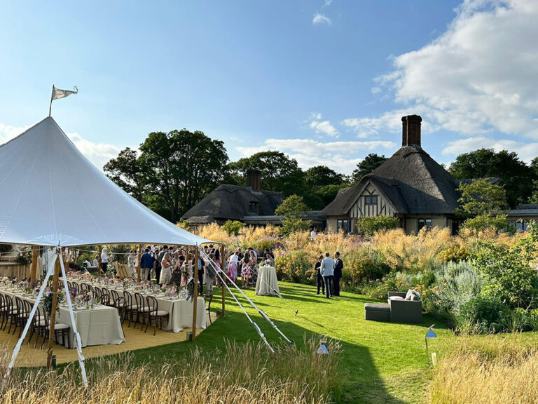 Marquee and long tables on the lawn beside a thatched house, private estate, The Admirable Crichton