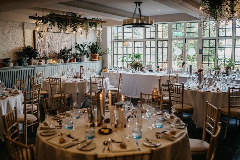 Round wedding-breakfast tables with tall tapers and trailing greenery, The Bay Tree Hotel