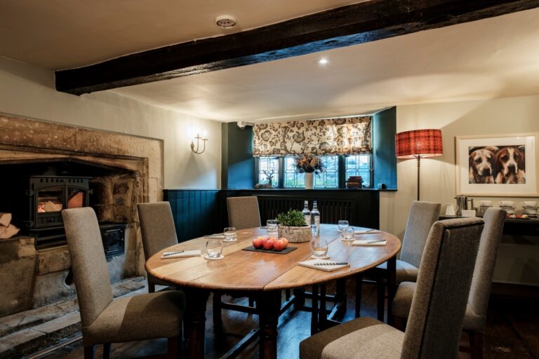 A private dining room with an oval table beside a stone fireplace, The Bay Tree Hotel