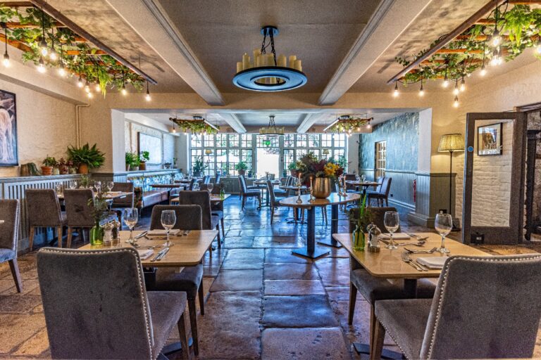 The Restaurant laid for dinner, flagstone floor and festoon lights, The Bay Tree Hotel