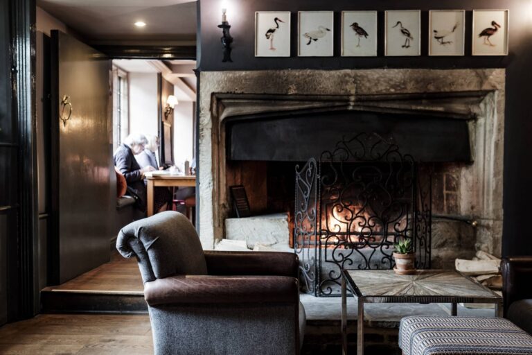 The inglenook fireplace and armchairs in the panelled sitting room, The Bay Tree Hotel