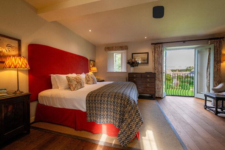 The Wisdom Superior Garden Room with a red upholstered headboard, The Bay Tree Hotel