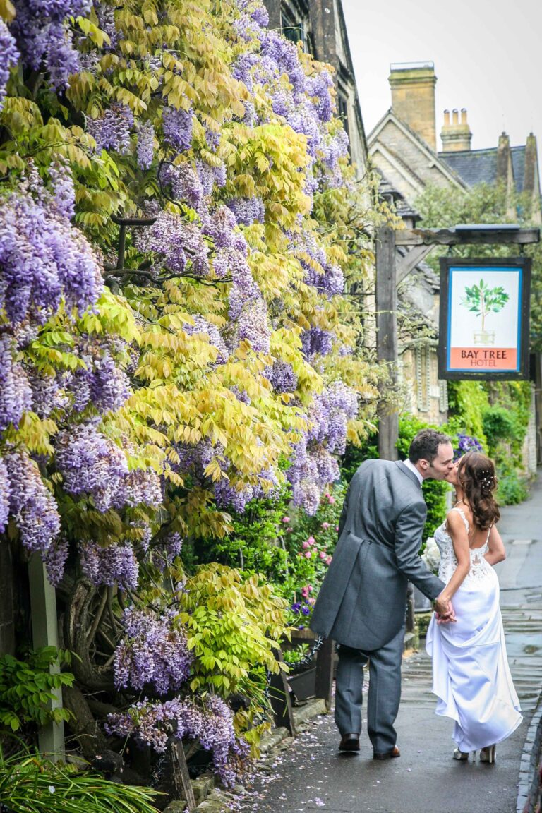 The couple kissing beneath the wisteria-covered wall beside the hotel sign, The Bay Tree Hotel