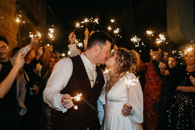 A sparkler send-off, the couple kissing amid guests, The Bay Tree Hotel