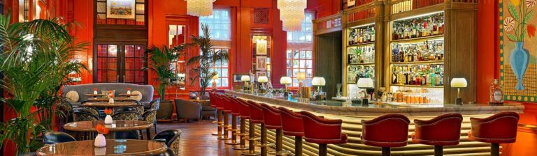 The Coral Room, with its coral-painted walls, palms, Murano glass chandeliers and long curved bar, The Bloomsbury