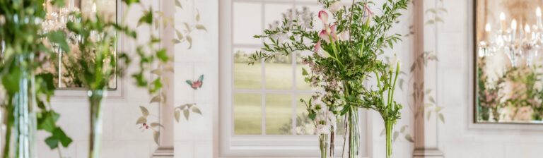 Detail of the Adam Ellis Studio garden wallpaper in Queen Mary Hall, with painted butterflies behind glass vases of flowers, The Bloomsbury