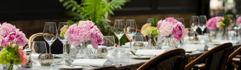 Peonies in small vases and glassware along a table on Dalloway Terrace, The Bloomsbury