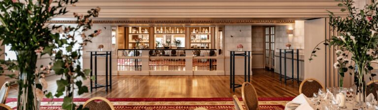 The separate bar area at one end of Queen Mary Hall, with a timber floor and high cocktail tables, The Bloomsbury