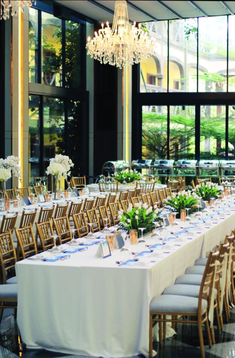 Long reception table with floral arrangements by the glass walls, The Chateau Spa and Organic Wellness Resort