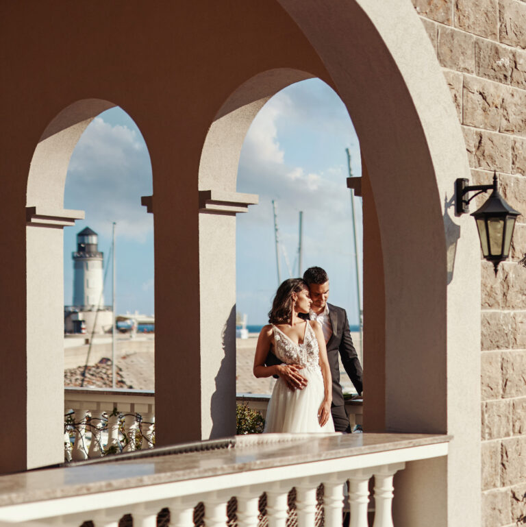 A couple beneath the arches with the lighthouse beyond, The Chedi Luštica Bay