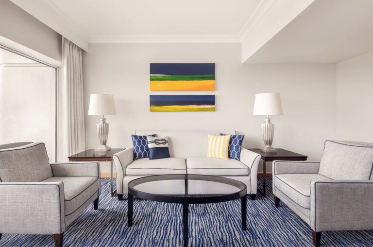 The sitting room of a Chelsea Suite, with a sofa, two armchairs and a striped blue carpet, The Chelsea Harbour Hotel