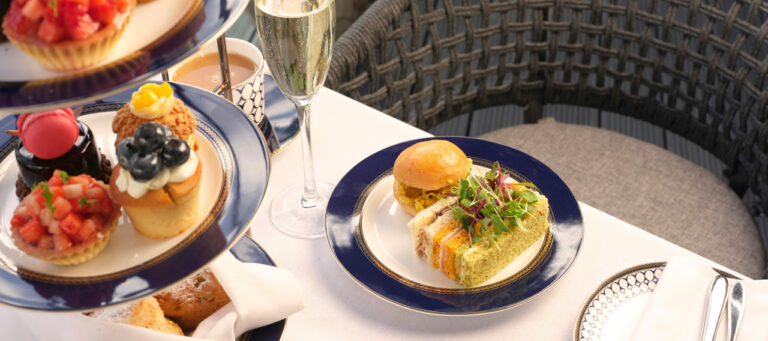 Afternoon tea on a tiered stand with fruit tarts, sandwiches and a glass of Champagne, The Chelsea Harbour Hotel