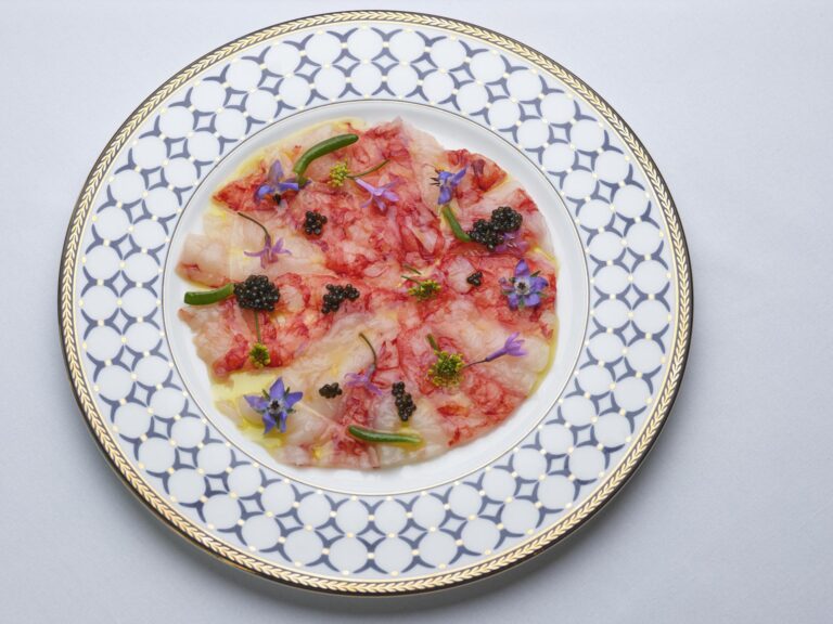 Red prawn carpaccio dressed with caviar and borage flowers on a patterned plate, The Chelsea Harbour Hotel