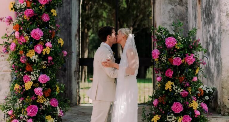 A couple kiss between arches of pink and yellow roses, The Courti Estate