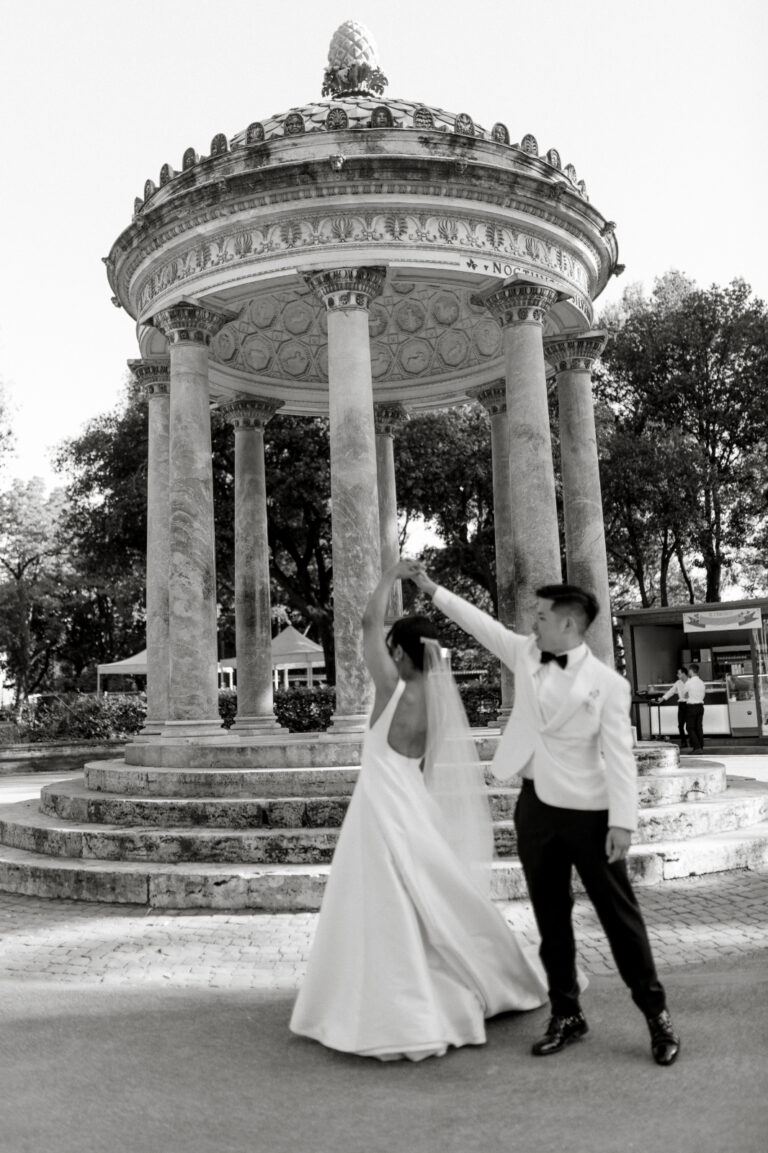 The couple dancing in front of a round columned temple in black and white, The Dream Wedding Lab