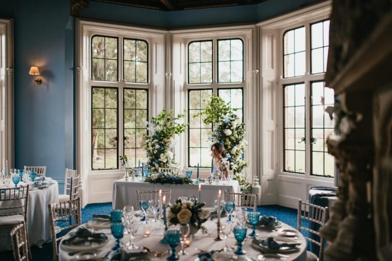 A reception dining room with a bay window and blue-glass styled tables, The Elvetham