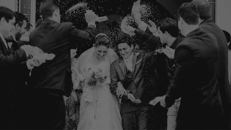 A bride and groom surrounded by guests as they leave the ceremony, in black and white, The Event Studio