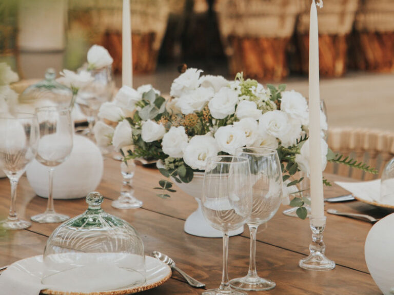 White roses, tall candles and glassware on a wooden table, The Event Studio