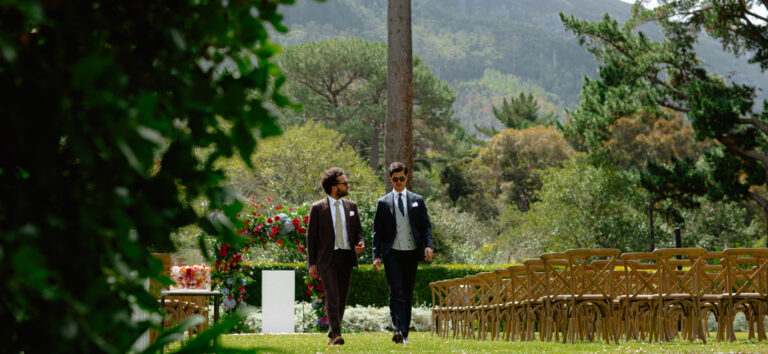 Two men in suits walking towards the ceremony seating in the garden, The Forum Embassy Hill