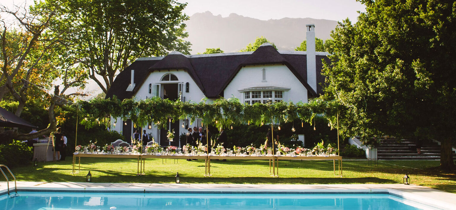 The house and swimming pool, set for an outdoor dinner