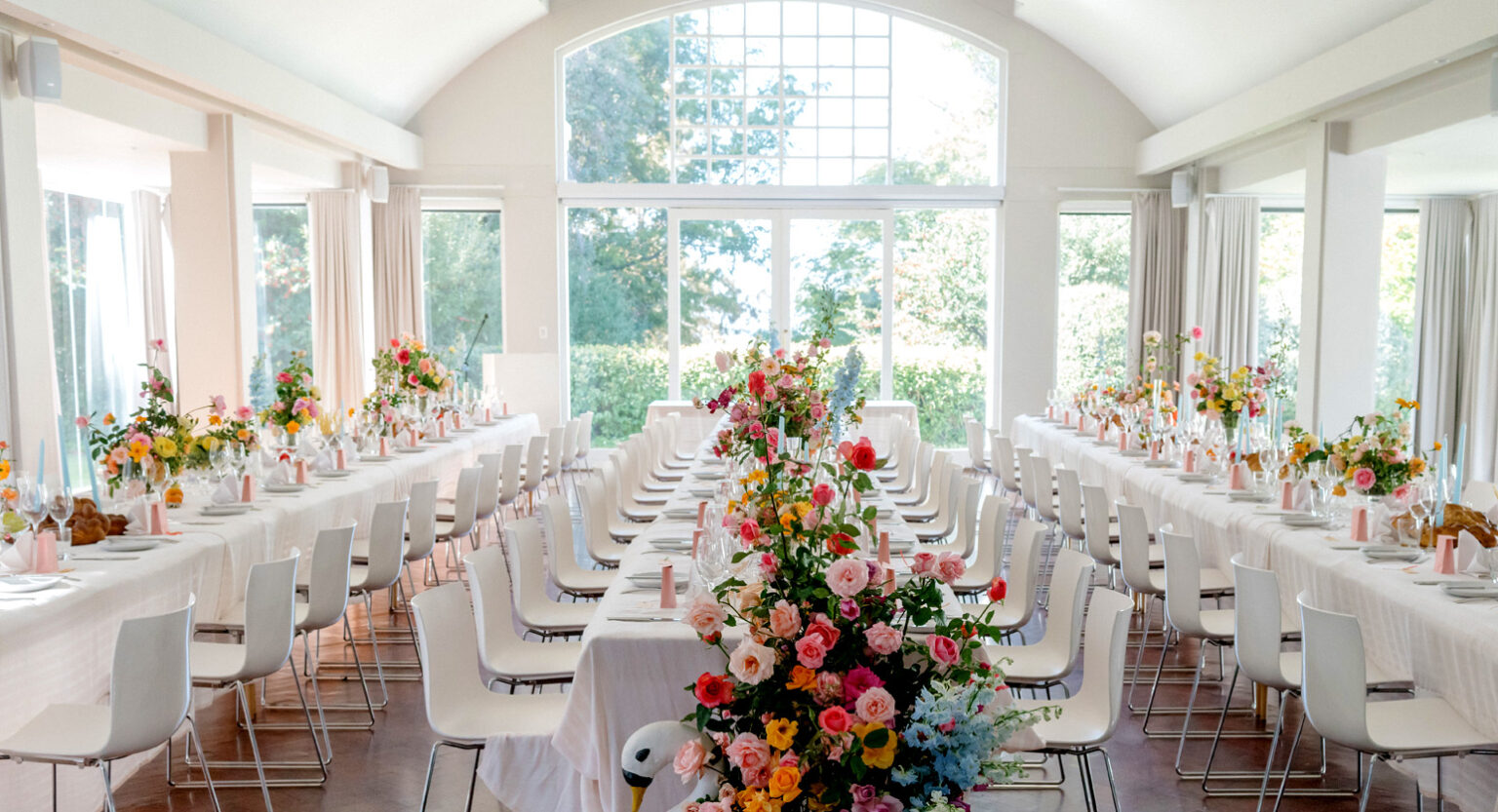 The light-filled hall set with long tables and flowers