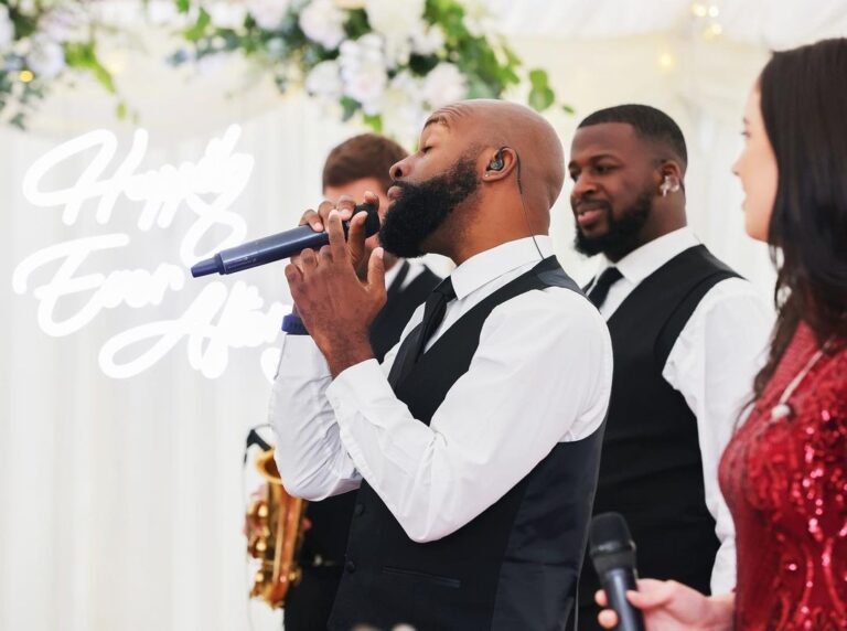 Vocalists performing in front of a neon Happily Ever After sign, The Function Band