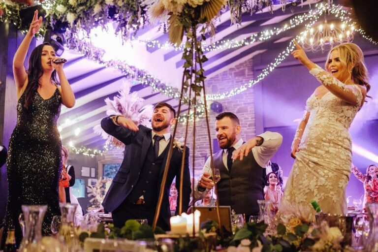 Two vocalists performing beside the bride and groom on the top table, floral installation overhead, The Function Band