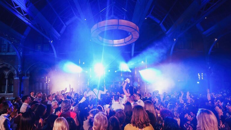 Packed dance floor under blue stage lights in a vaulted hall, The Function Band