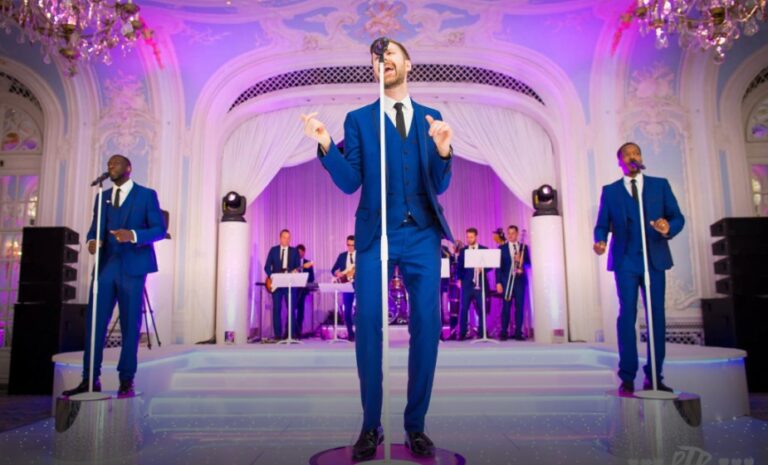 Lead vocalist with backing singers on a staged platform in an ornate ballroom, The Function Band