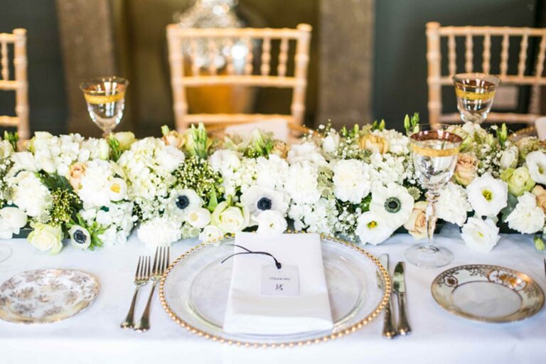 A tablescape with a white floral runner and gilt-rimmed glasses, The George in Rye