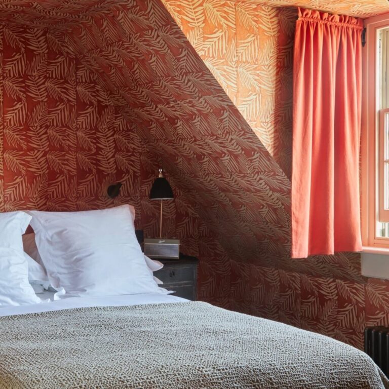 A guest bedroom beneath the eaves, in warm terracotta, The George in Rye