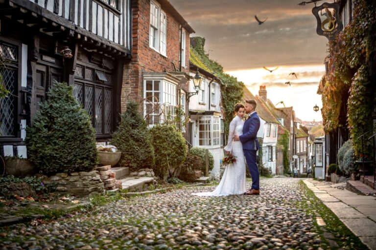 A couple on Rye's cobbled Mermaid Street, The George in Rye
