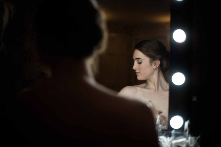 The bride getting ready at a lit mirror, The George in Rye