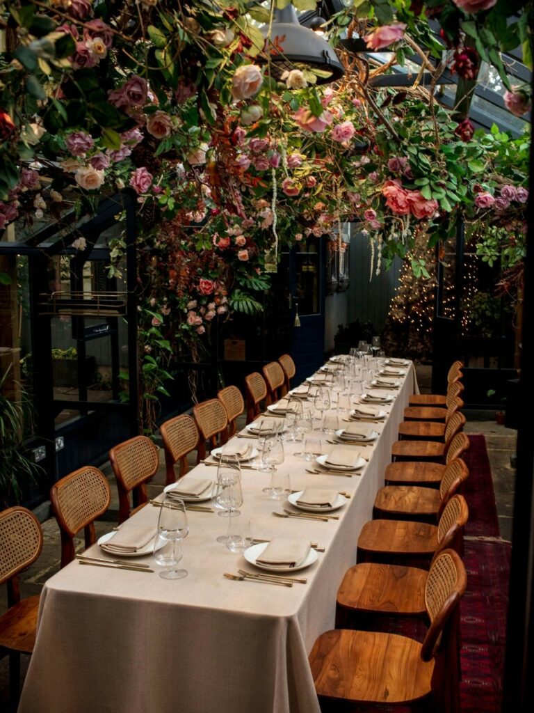 The long table running the length of the blossom-hung glasshouse, The Greenhouses
