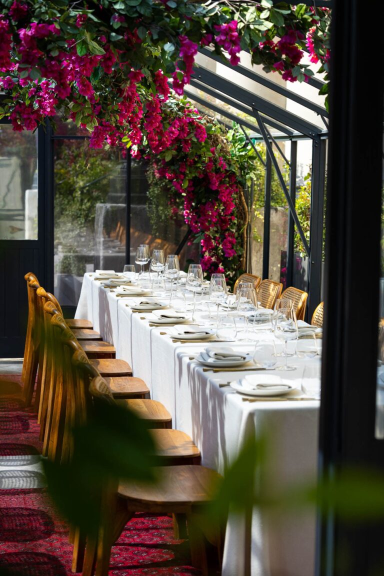 A long white table beneath magenta bougainvillea, The Greenhouses
